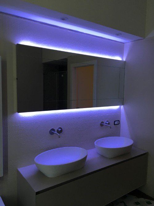 Mobile bagno moderno con due lavabi a ciotola bianchi, ampio specchio e illuminazione a LED viola.