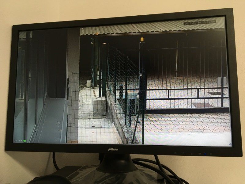 Monitor di computer che mostra un corridoio interno buio con ringhiere metalliche e una scala.