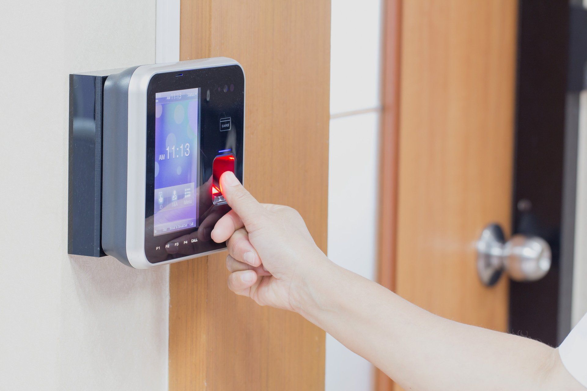 A person is using a fingerprint scanner to open a door.