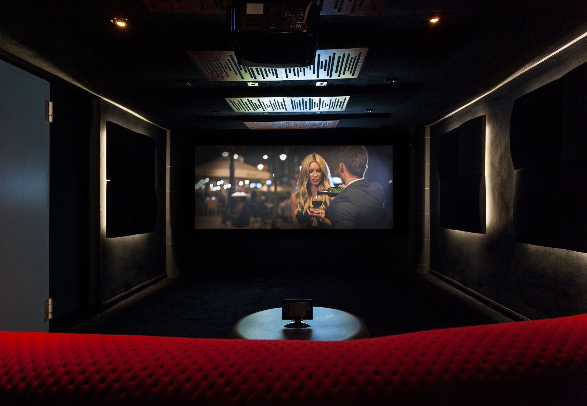 A home theater with a large screen and a red couch.