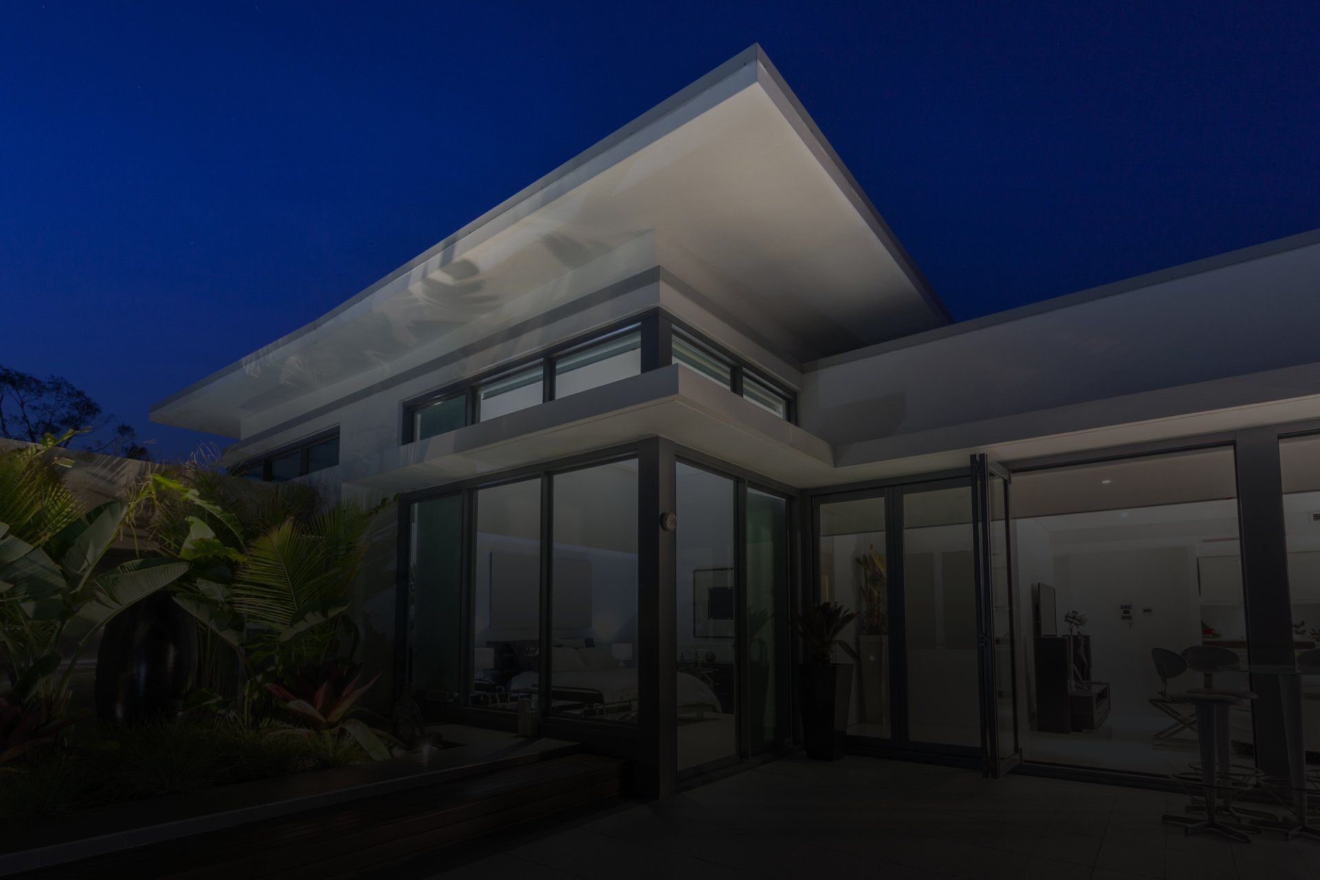 A modern house with a lot of windows is lit up at night.