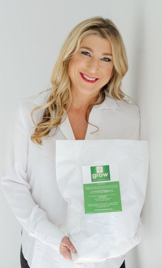 Woman with blonde hair smiling, holding a bag of