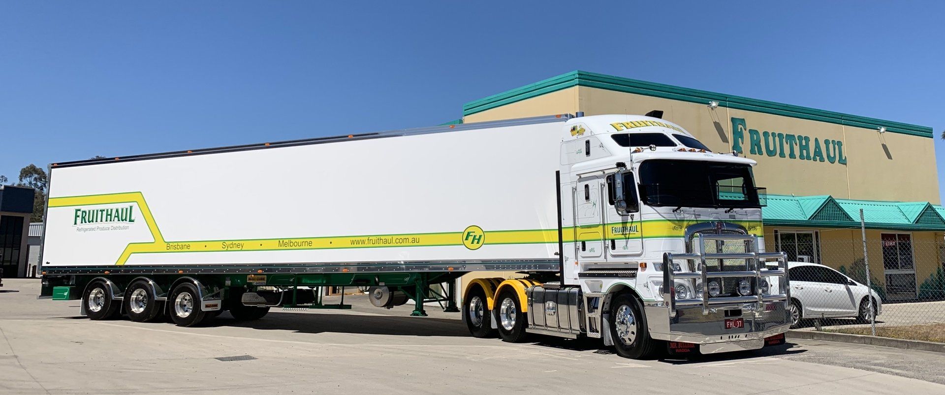 White Fruit Haul semi-truck parked in front of a Fruit Haul building.
