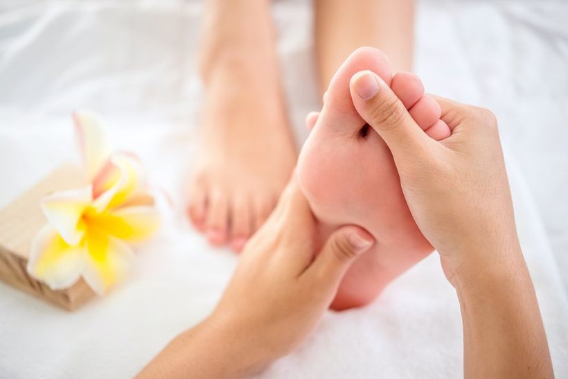 Close up of hands doing foot reflexology massage on female foot.