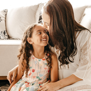 A woman and young girl are sitting on the floor in front of a couch.