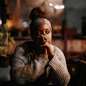A woman is sitting at a table with her hands on her face.
