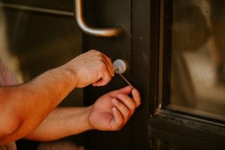 Hands unlocking a dark door with a key