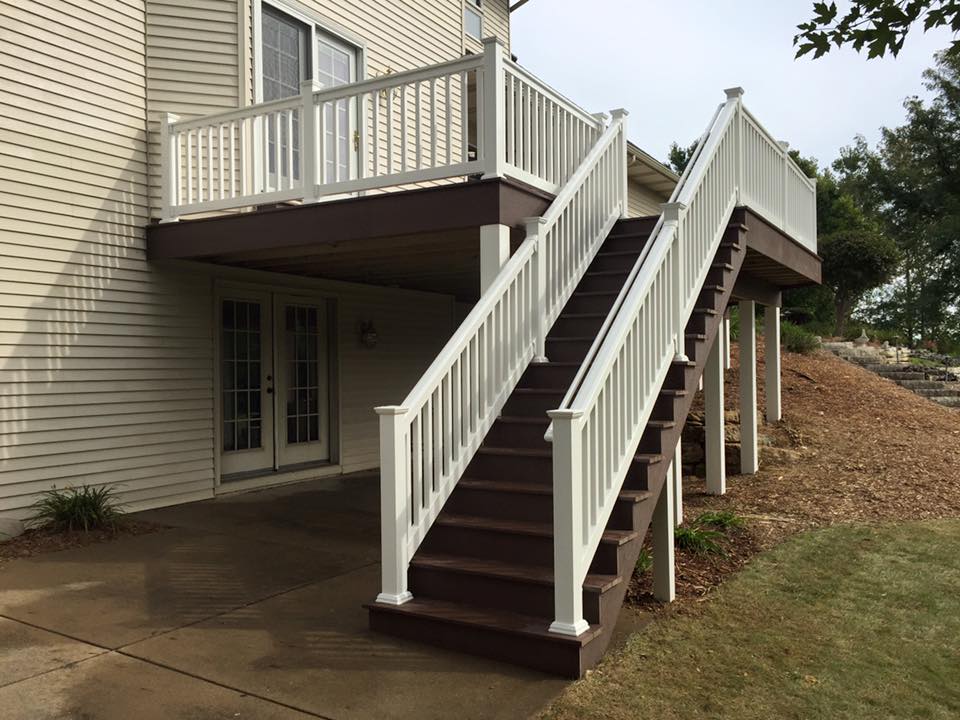 A deck with stairs leading up to it and a white railing