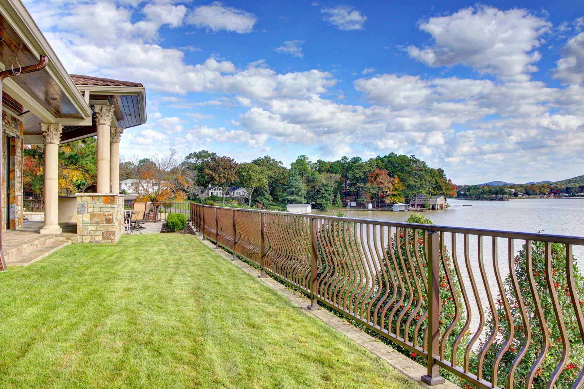 A house with a fence surrounding it and a view of a lake.