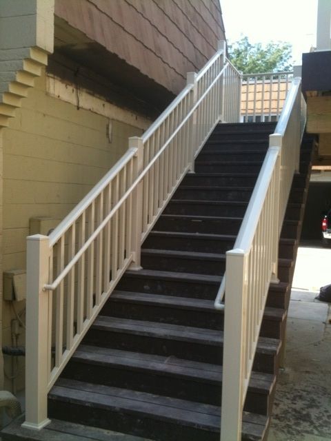 A set of stairs with a white railing leading up to a building