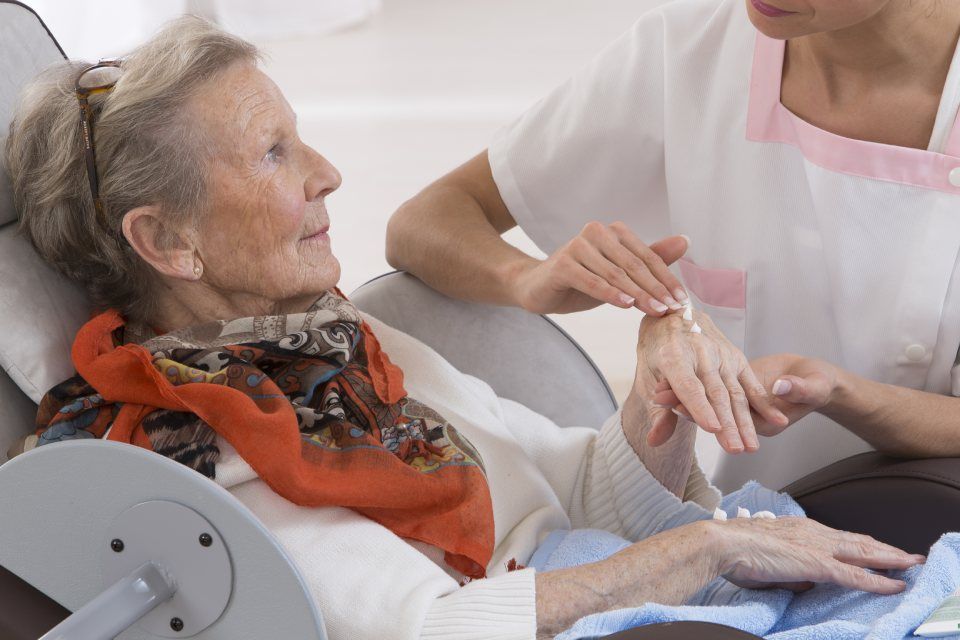 woman applying cream on an old lady hand