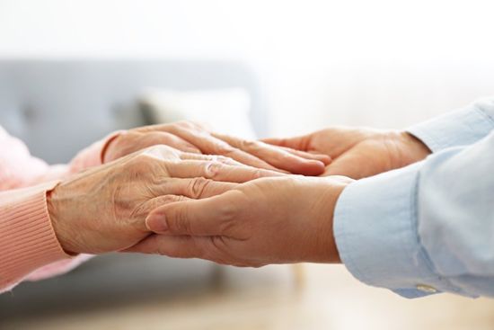 caregiver holding hands of an old woman