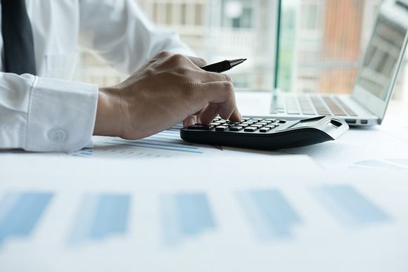 Revisore contabile impegnato con calcolatrice e documenti