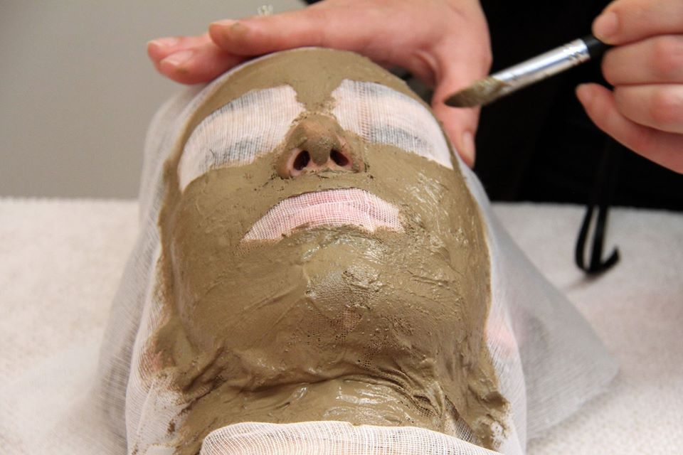 Persona che riceve l'applicazione di una maschera facciale. La maschera viene applicata sul viso con un pennello, proteggendo la zona degli occhi e delle labbra.