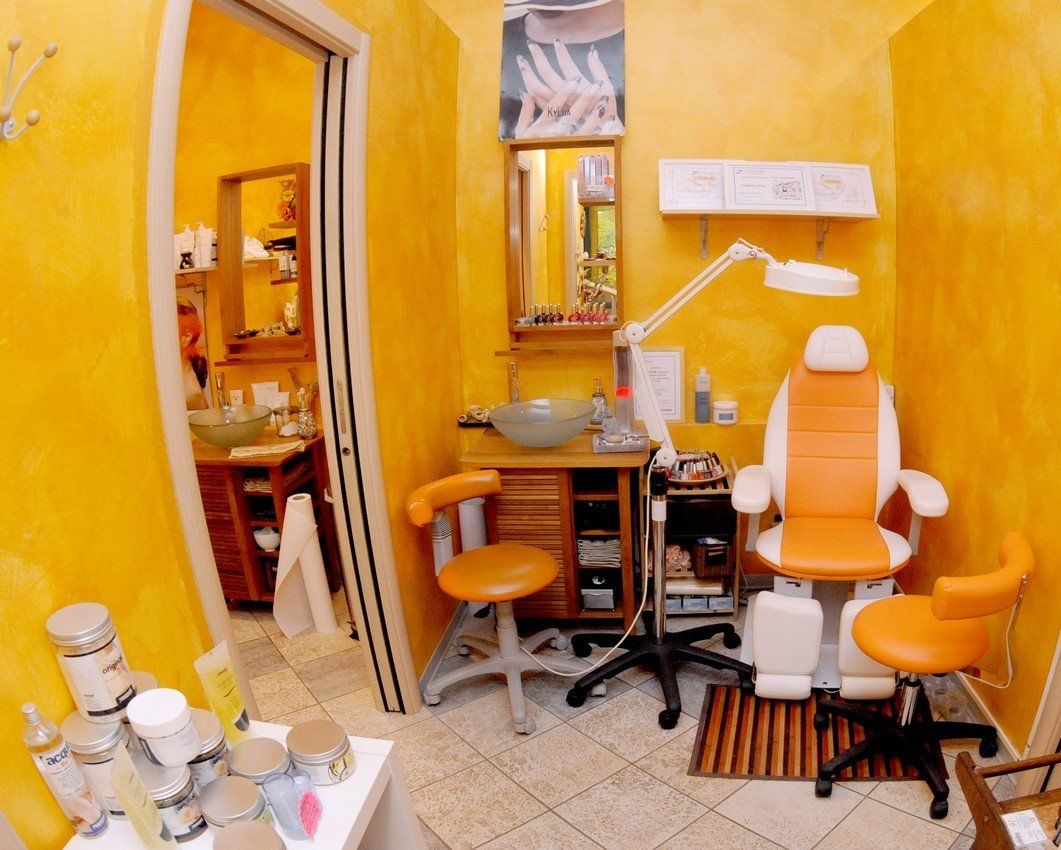 Interno di un salone di bellezza giallo con poltrona per pedicure, strumenti e porta aperta.