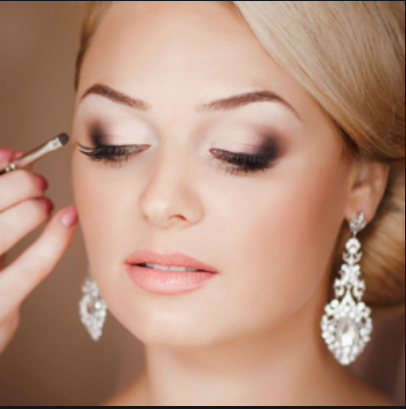 Donna che si sottopone al trucco degli occhi, con grandi orecchini di cristallo.