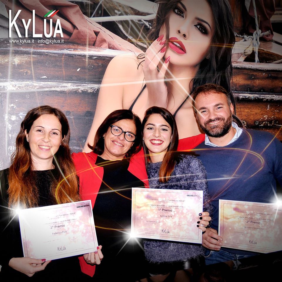 Quattro persone con in mano dei certificati davanti a uno sfondo promozionale raffigurante una donna.