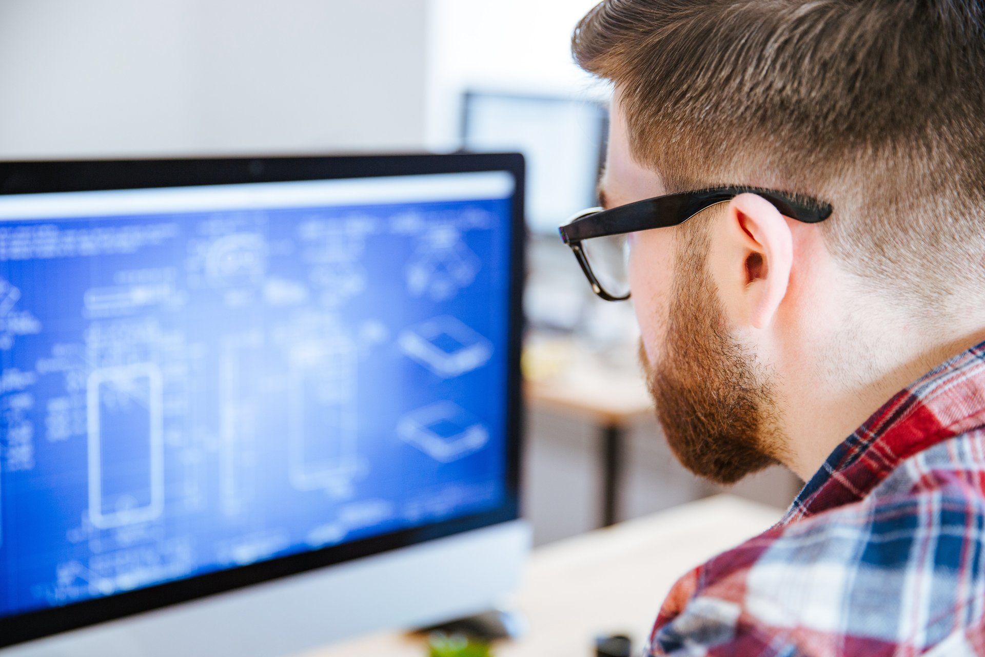 A man wearing glasses is looking at a computer screen.