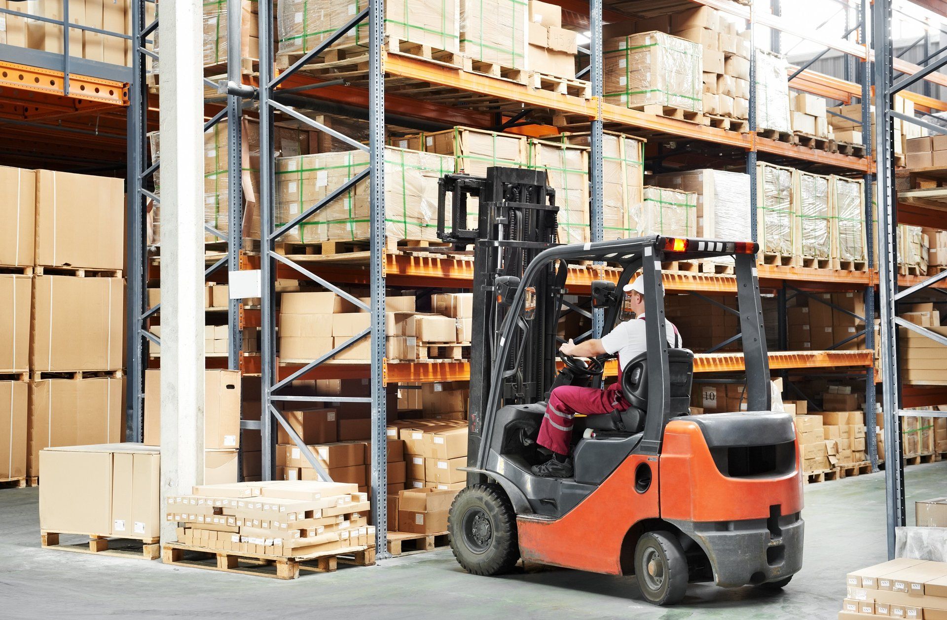 A man is driving a forklift in a warehouse.