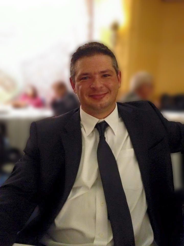 A man in a suit and tie is smiling for the camera