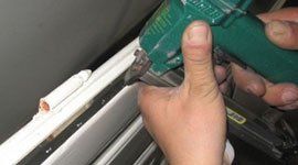 le mani di un operaio che lavora su infissi