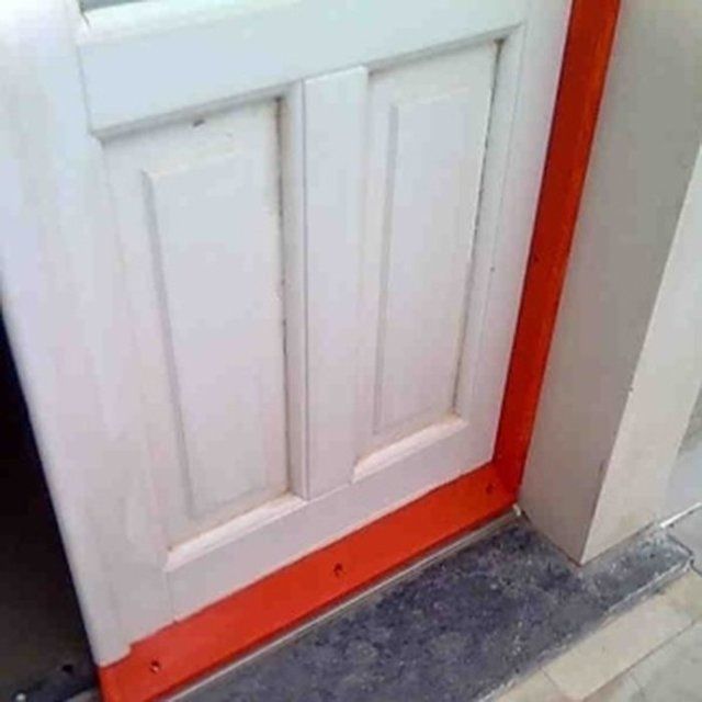 una porta in legno bianca con paraspifferi rosso