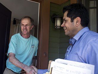 Two men are shaking hands in front of a door.