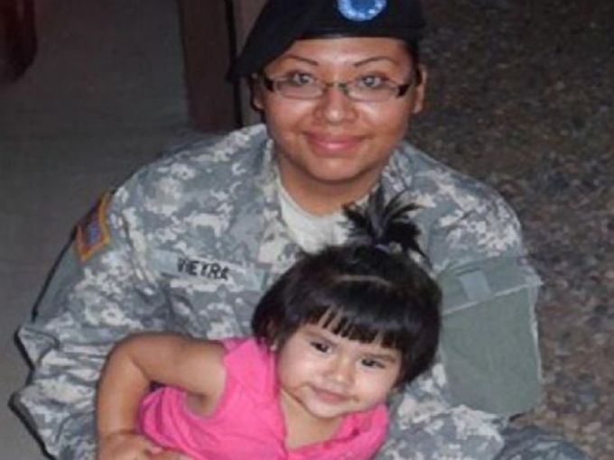 A woman in a military uniform holds a little girl