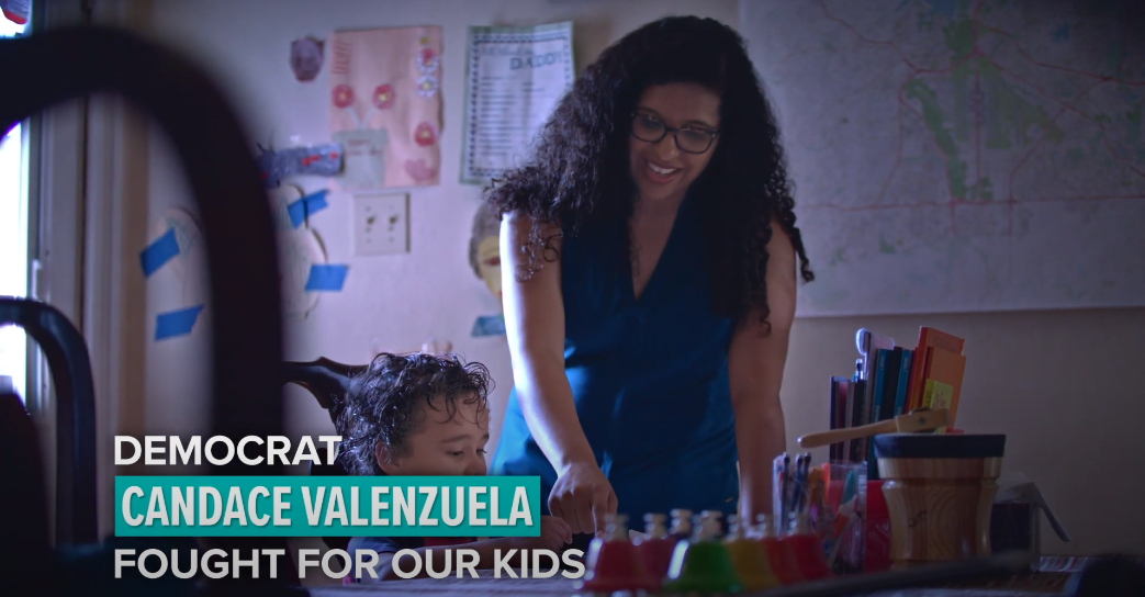A woman is standing next to a child in a room.