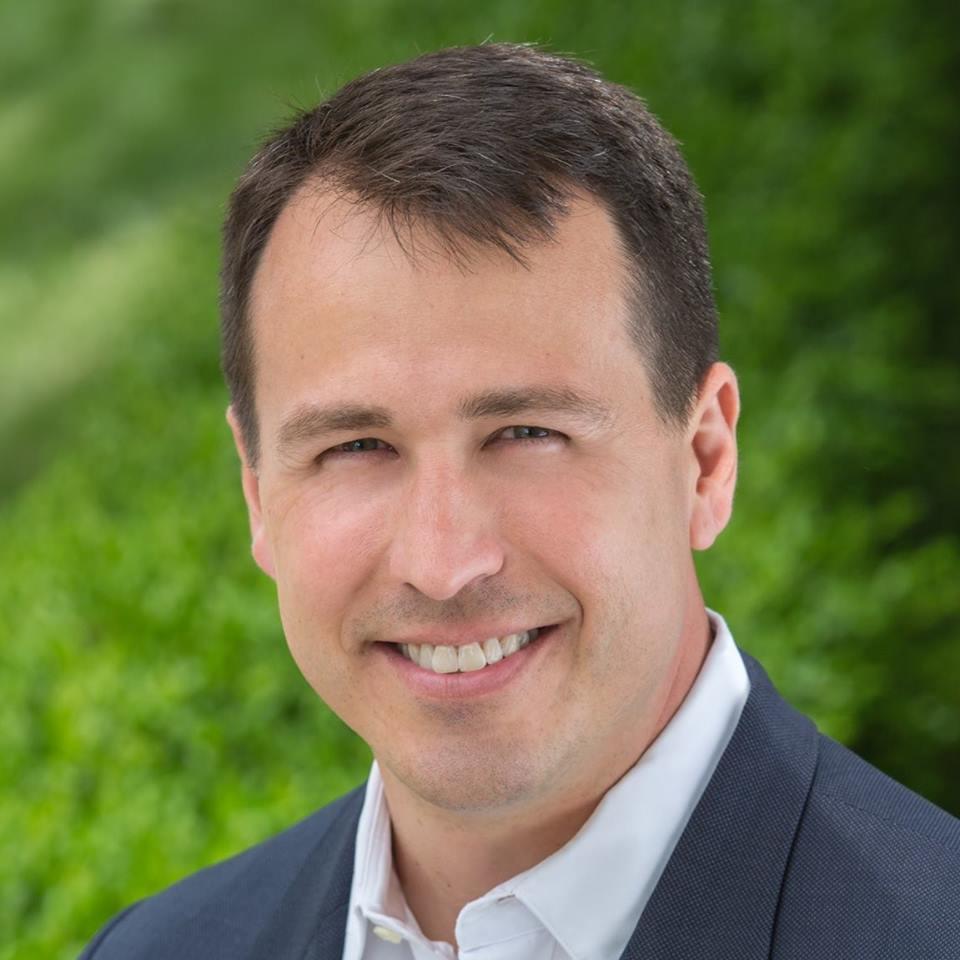 A man in a suit and white shirt is smiling for the camera.