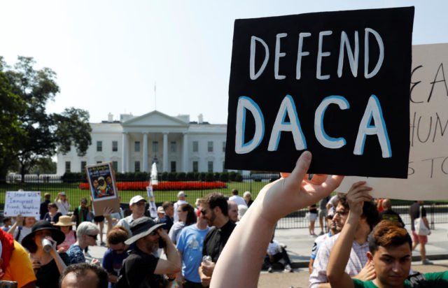 A protester holds up a sign that says defend daca