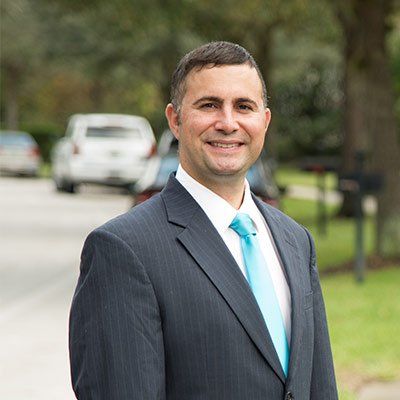 A man in a suit and tie is standing in front of a street.