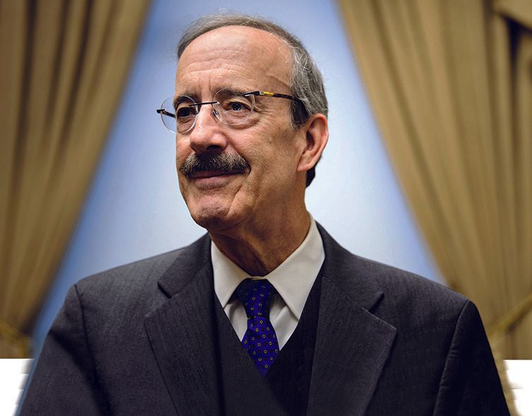 A man with glasses and a mustache is wearing a suit and tie