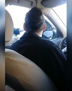 A man is sitting in the driver 's seat of a car.