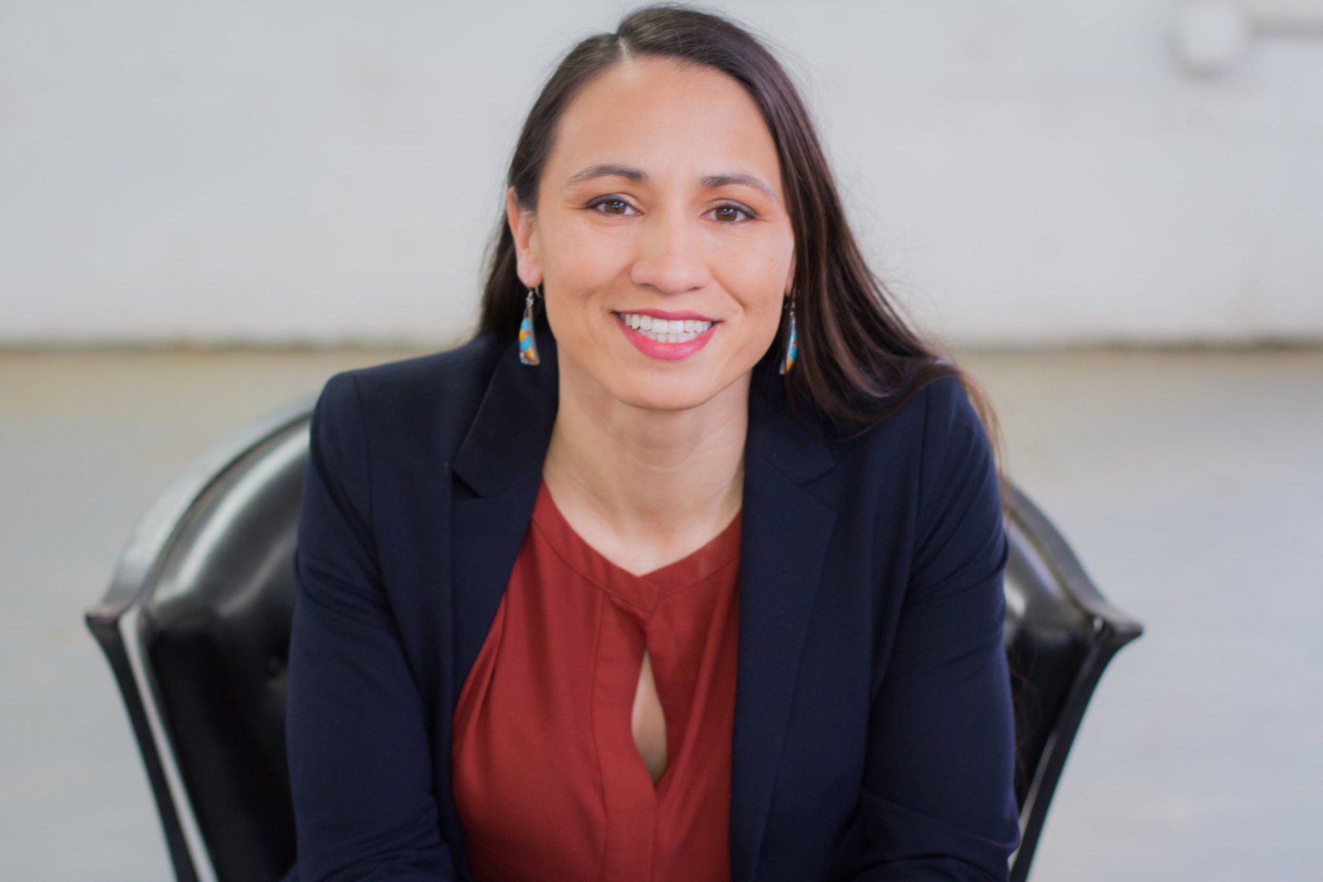 A woman is sitting in a chair and smiling for the camera.