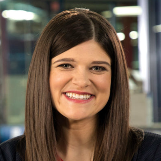 A woman with long brown hair is smiling for the camera