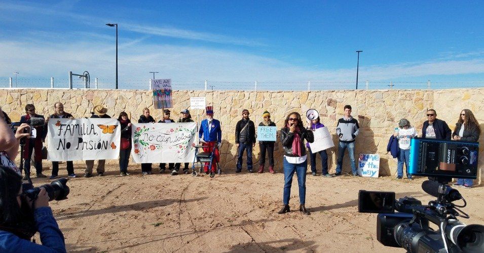 A woman is standing in front of a group of people holding signs.