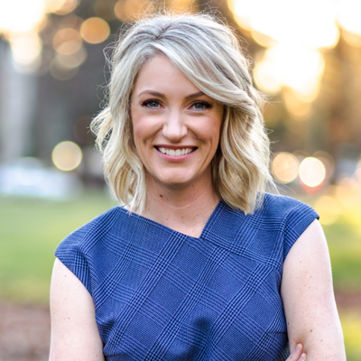 A woman in a blue dress is smiling for the camera.