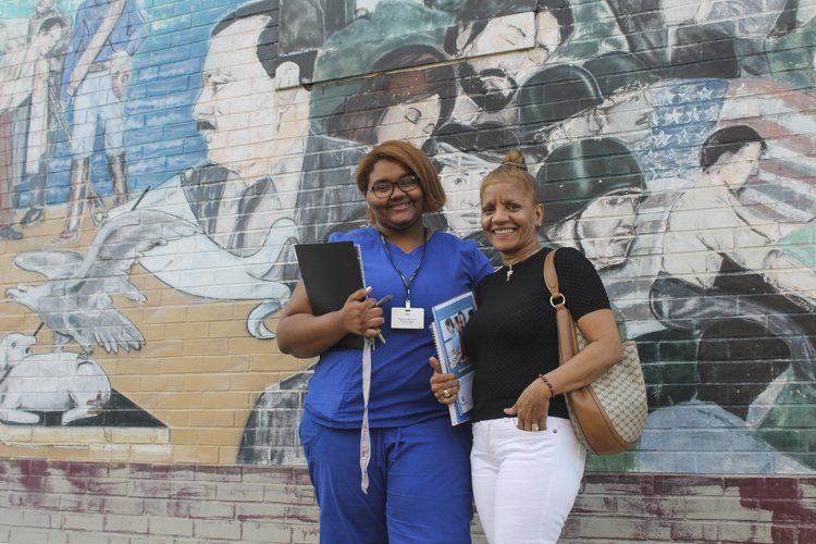 Two women are posing for a picture in front of a mural.