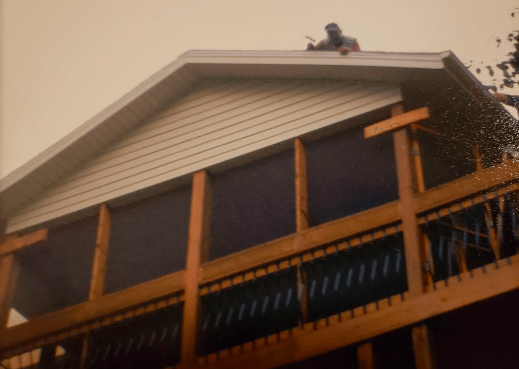 A man is standing on the roof of a house