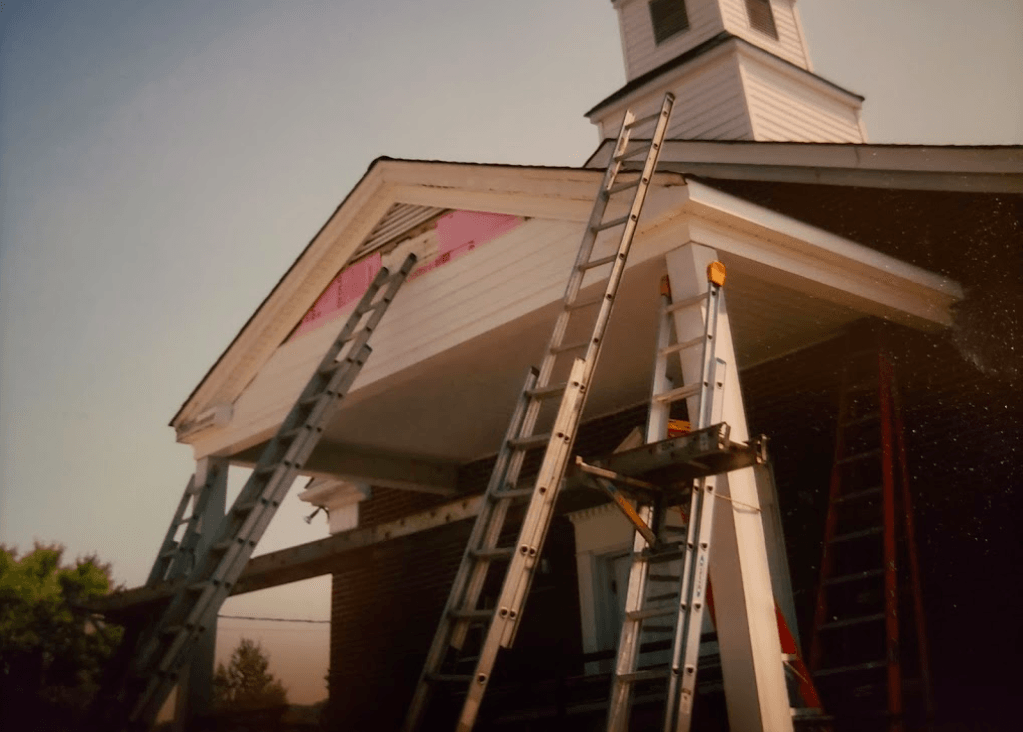 Two ladders are sitting on the side of a building