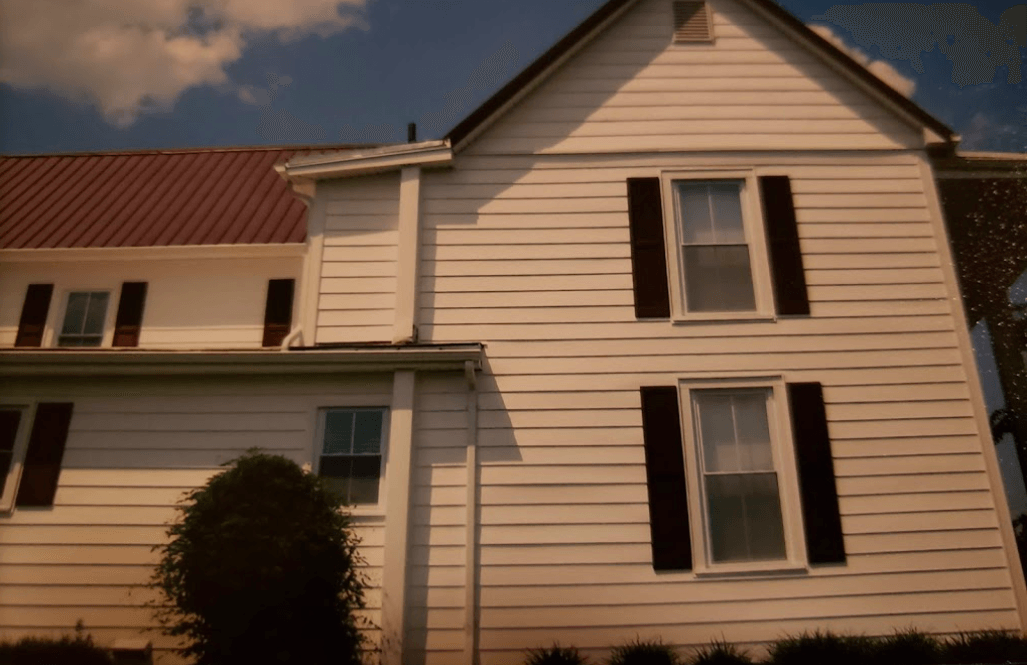 A white house with black shutters and a red roof
