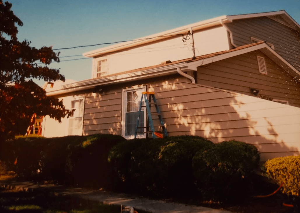 A man standing on a ladder in front of a house