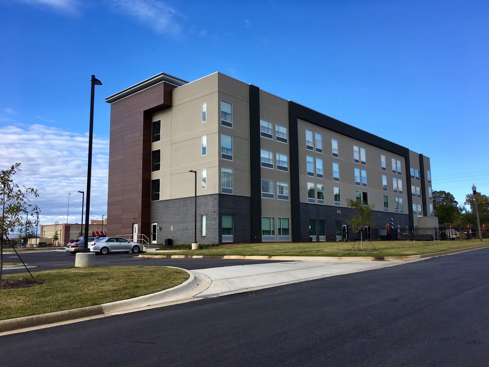 A large building with a lot of windows is sitting on the side of a road.