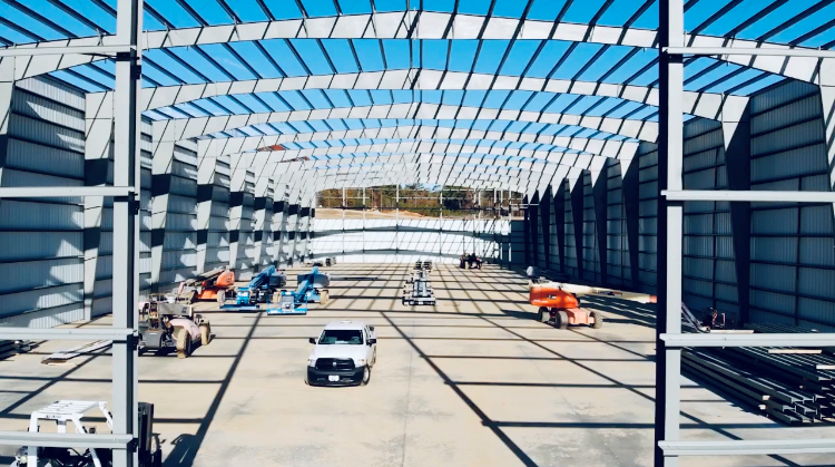 A white truck is driving through a large building under construction.