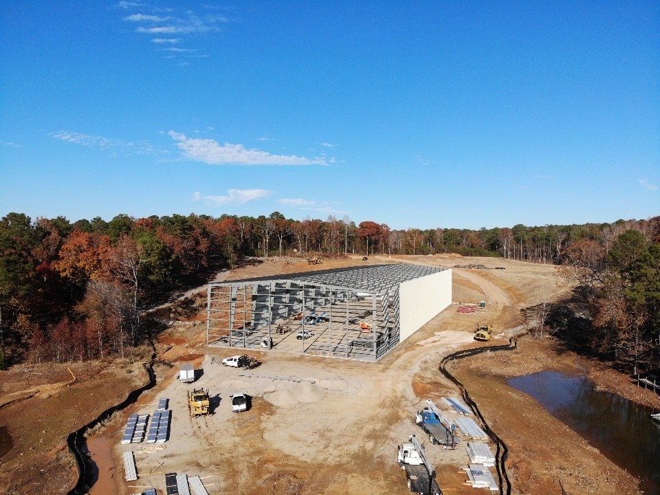 An aerial view of a large building under construction in the middle of a forest.