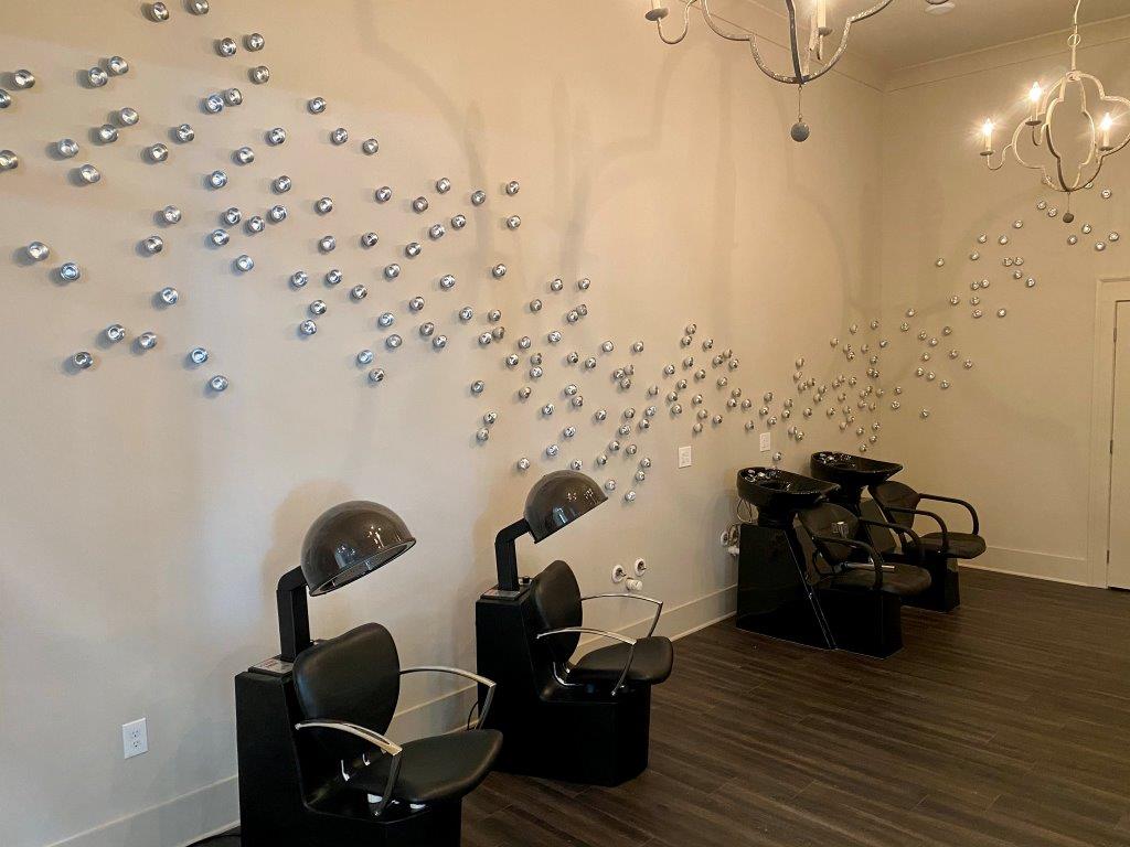 A room with a lot of hair salon chairs and a chandelier.