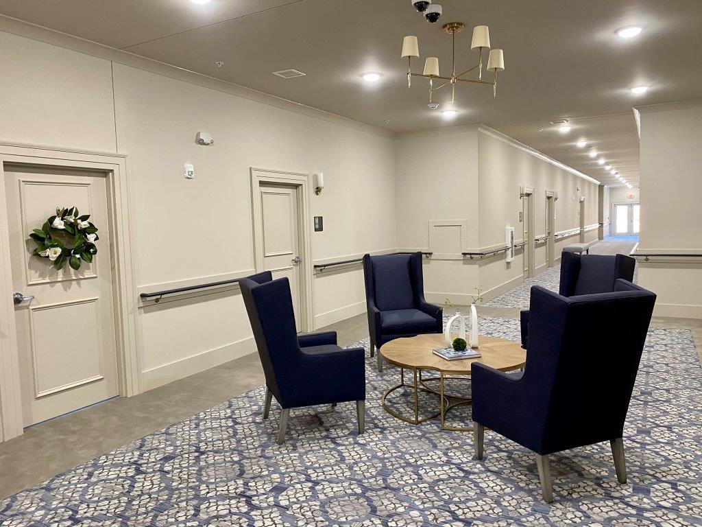 A long hallway with chairs and a table in a nursing home.