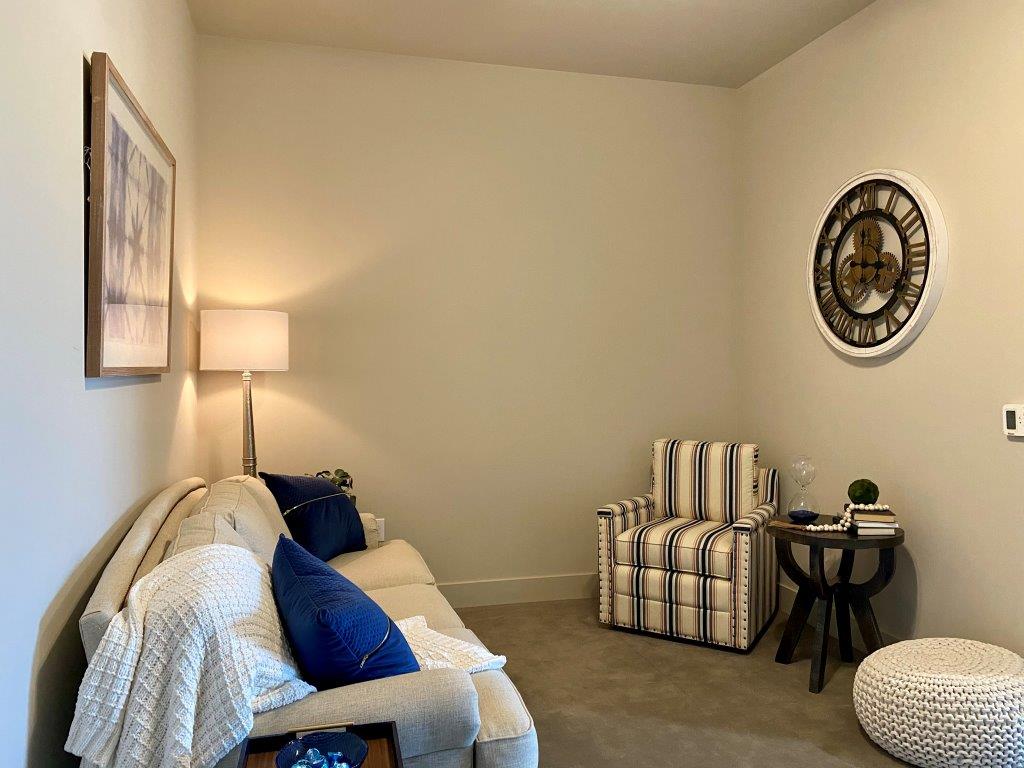 A living room with a couch , chair , table and clock on the wall.