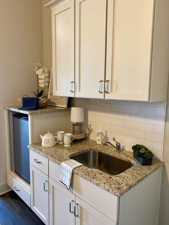 A kitchen with white cabinets , granite counter tops , a sink and a refrigerator.